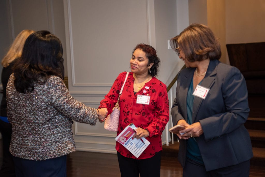 A woman shaking hand with another at a networking event.