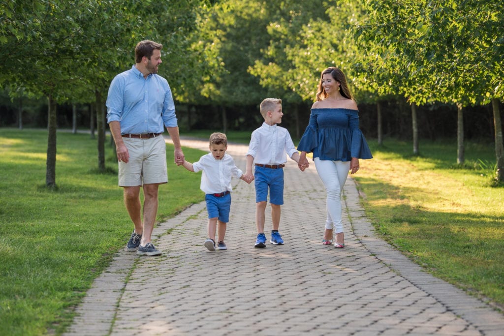 Family of 4 walking down a pathway at a park.