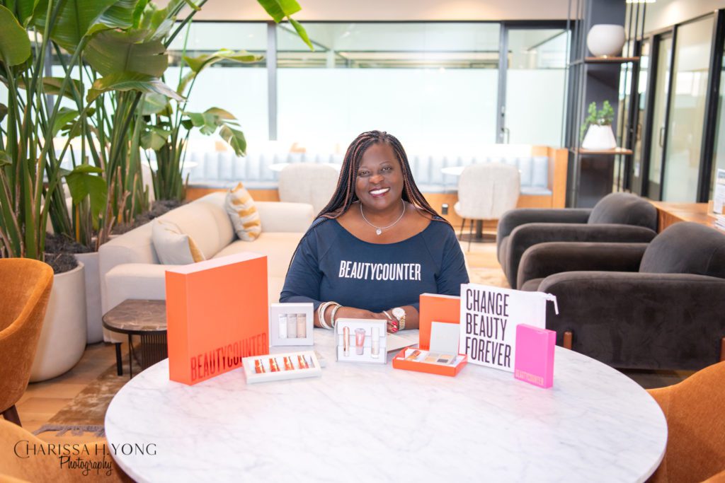 An African American woman sitting at a table with Beautycounter products.