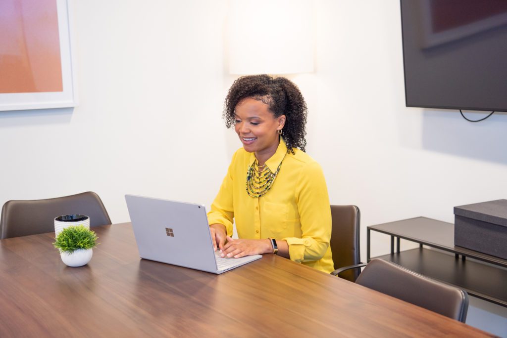 An African American woman sitting in a conference room and working on her laptop