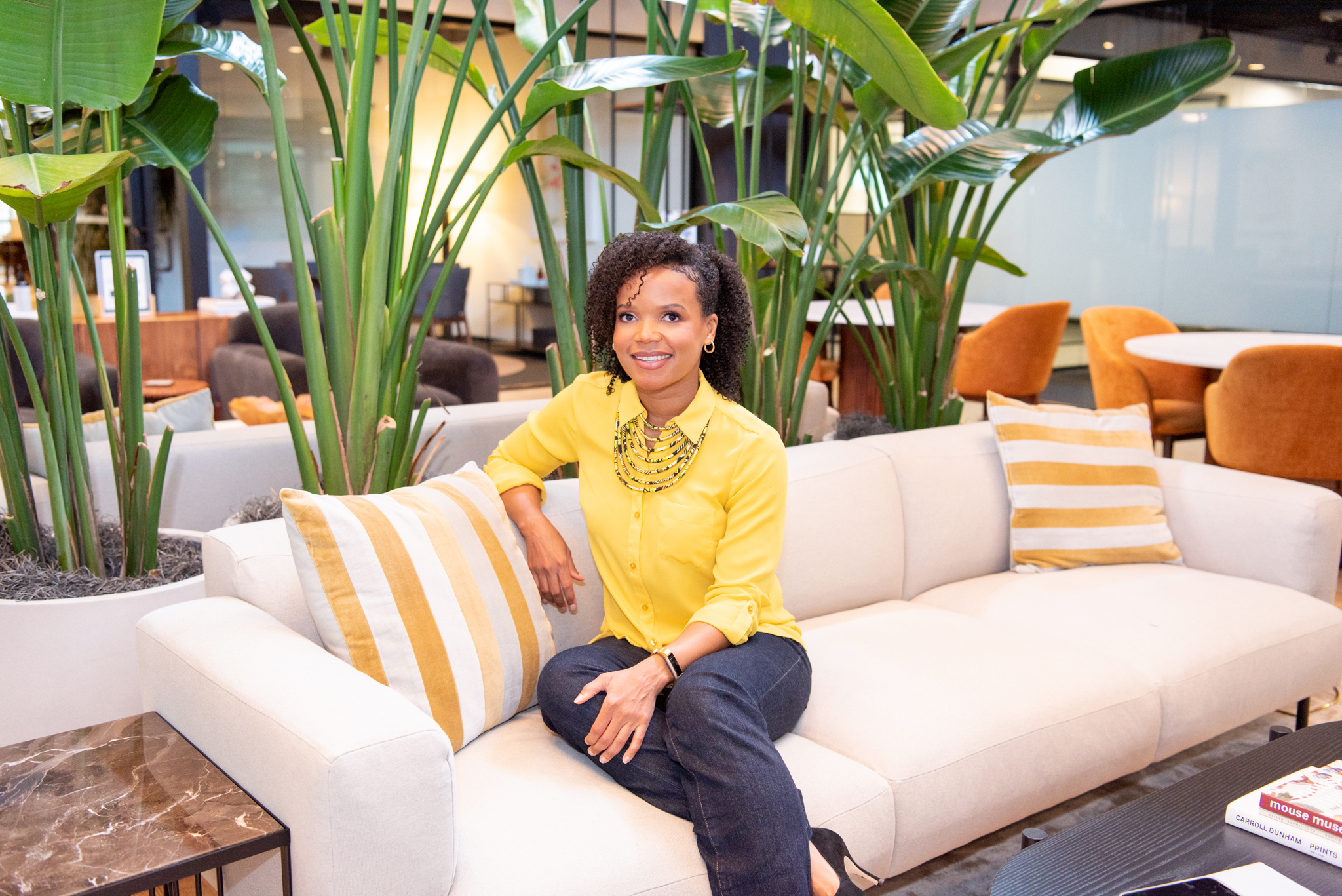 An African American woman sitting on a couch posing for her branding photoshoot.