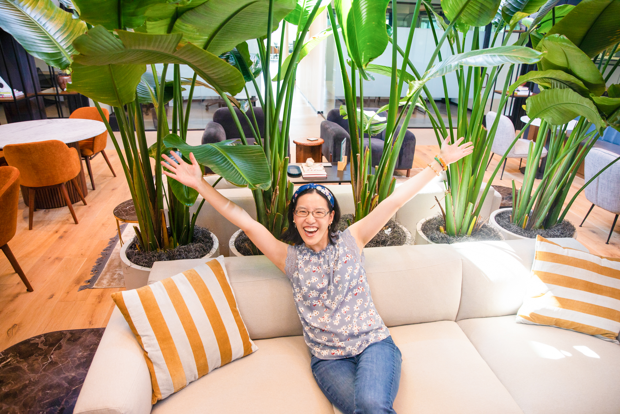 An Asian woman with her arms up showing excitement in a co-working space.