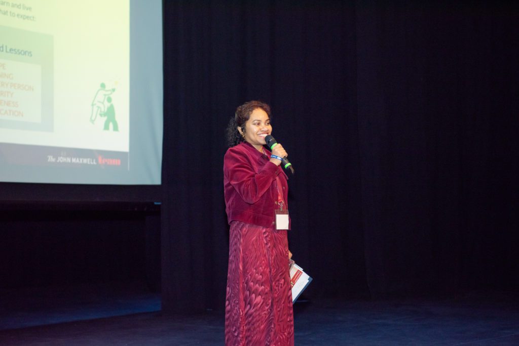 An Indian woman speaking on a stage at a leadership conference in Fairlawn, New Jersey.