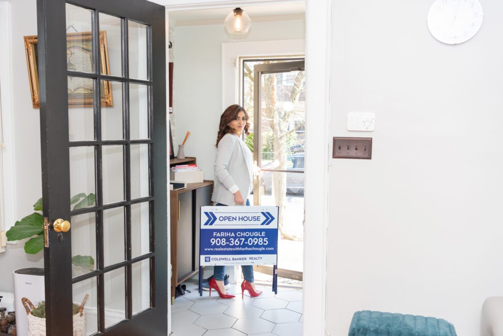 A real estate agent walking out the door with her open house sign.