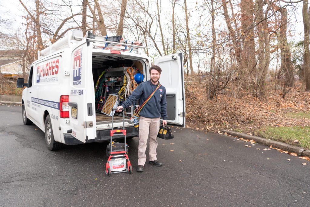 A male HVAC technician standing next to his HVAC truck.