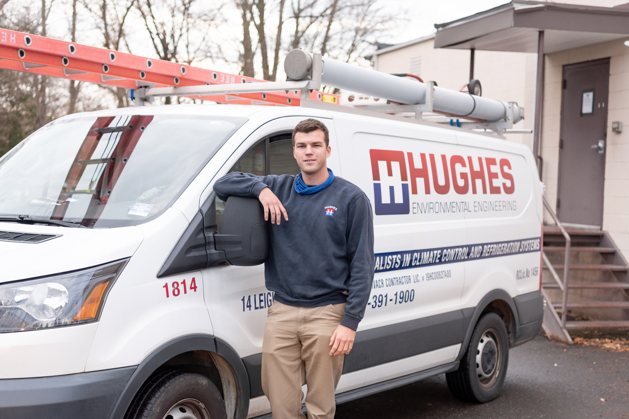 A male HVAC technician standing next to his HVAC truck.