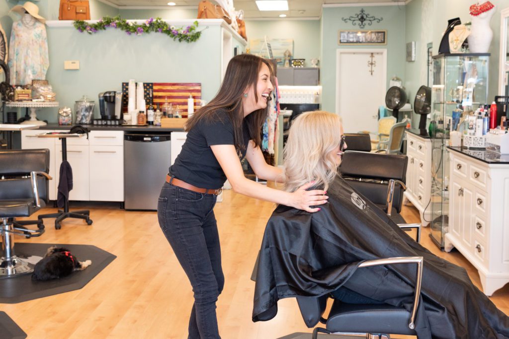 A female hair stylist and her client laughing and having a great time at the Revival Hair Studio in Dumont, New Jersey.