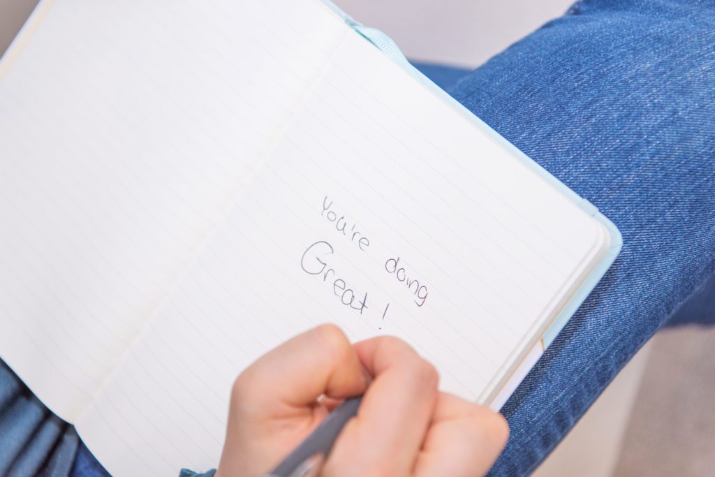 A female parent and family coach wrote "You're doing great!" in her notebook.