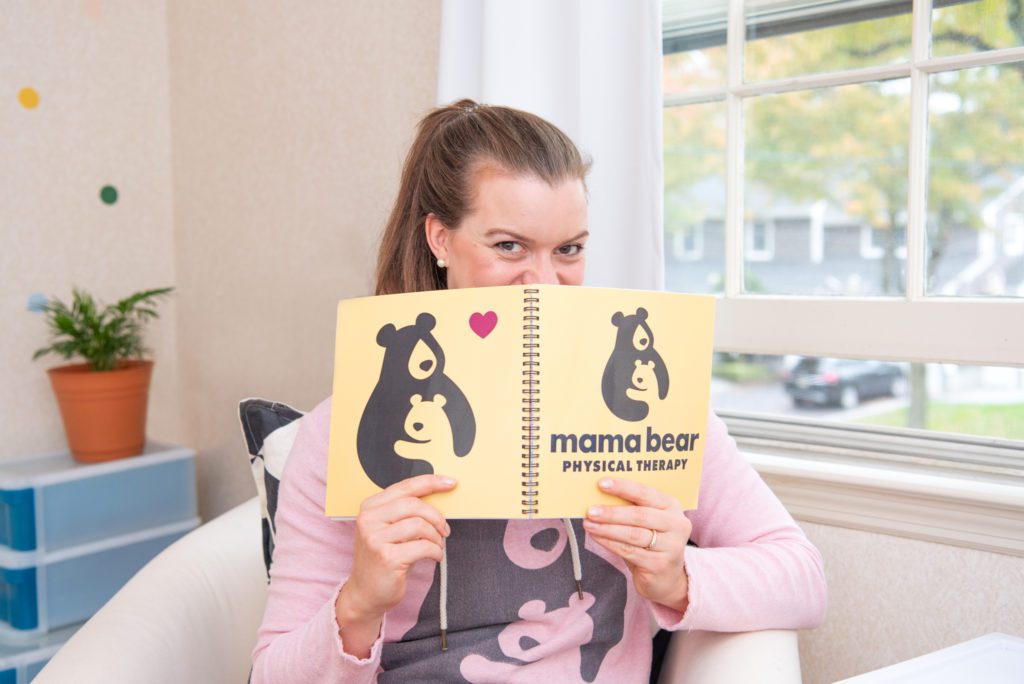 A female orthopedic and pelvic health physical therapist holding her Mama Bear Physical Therapy branded notebook.