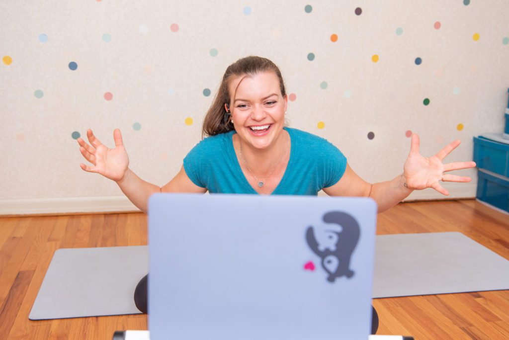 A female orthopedic and pelvic health physical therapist excited and cheering for her client during her virtual therapy session.