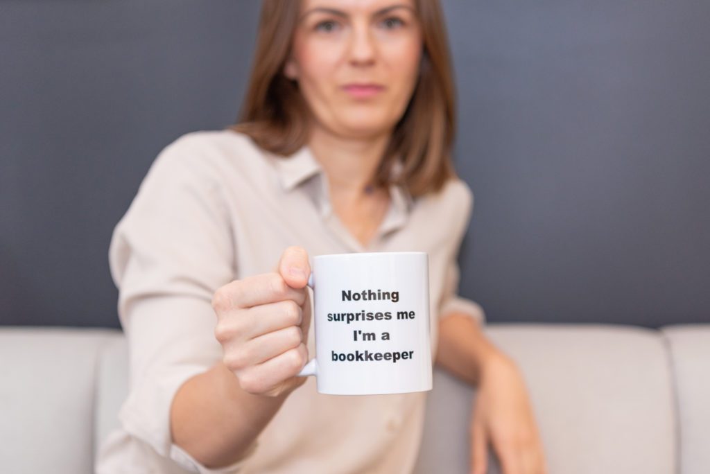 A female bookkeeper holding a mug with the quote: "Nothing surprises me. I'm a bookkeeper."