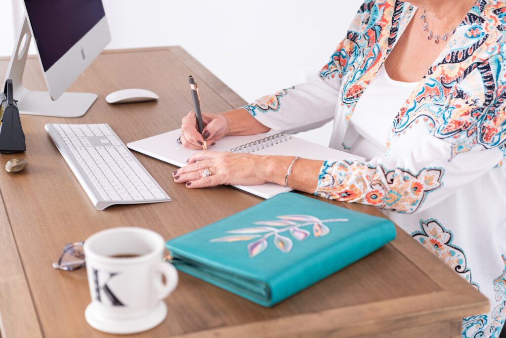 A female health and wellness coach writing in her journal in her office.