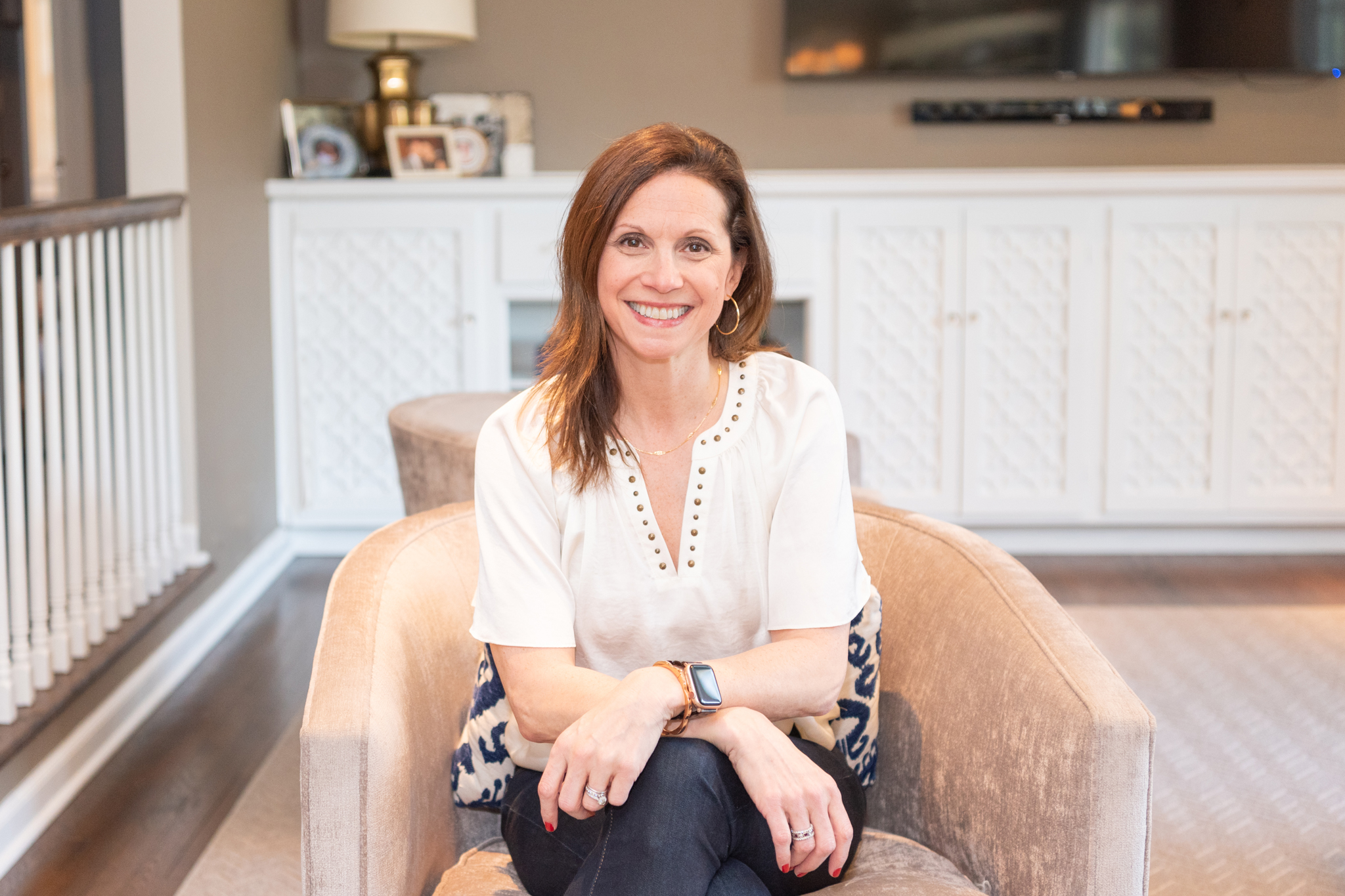 A female leadership coach sitting on her couch and smiling for her branding photoshoot.