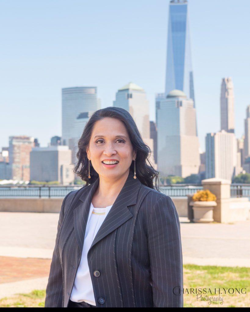 A female clinical laboratory scientist outdoor headshot with a New York City skyline and One World Trade Center as the background.