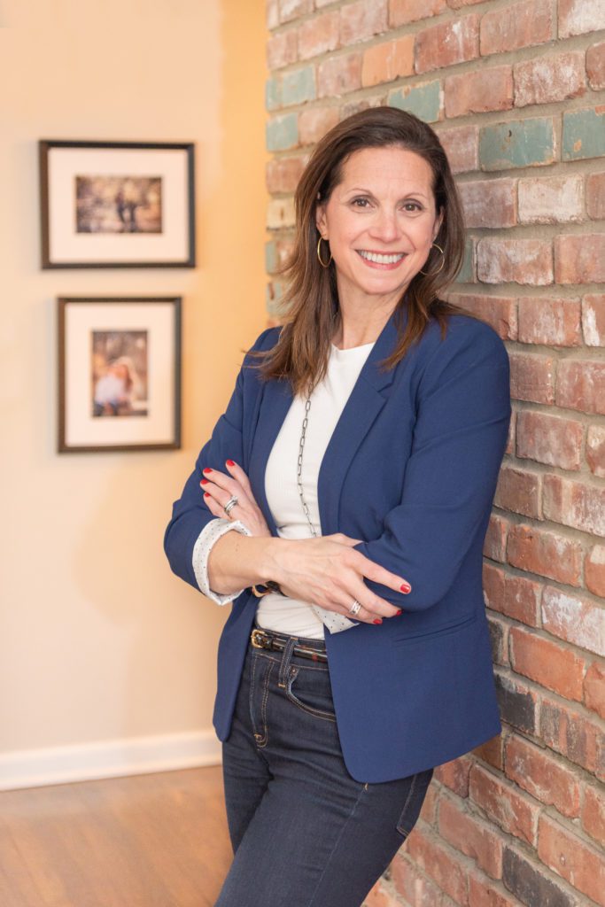A female leadership coach standing with her arm crossed and posing for her branding photoshoot.