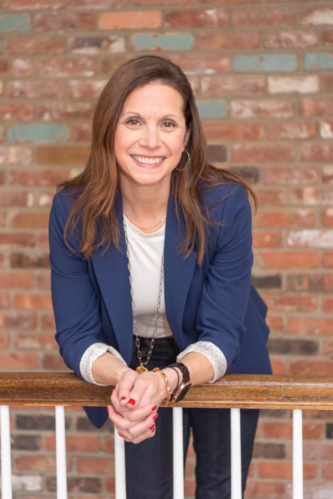 A female leadership coach standing and leaning on a railing and posing for her branding photoshoot.