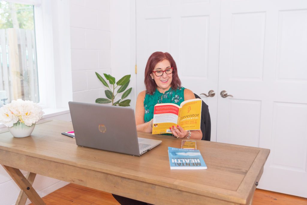 A female public relations expert sitting and reading a book in her office.