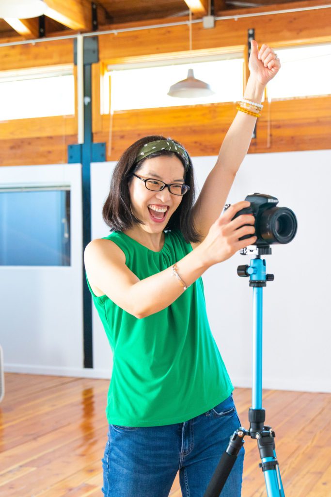 An Asian female personal branding photographer cheering on her clients while doing a photoshoot.