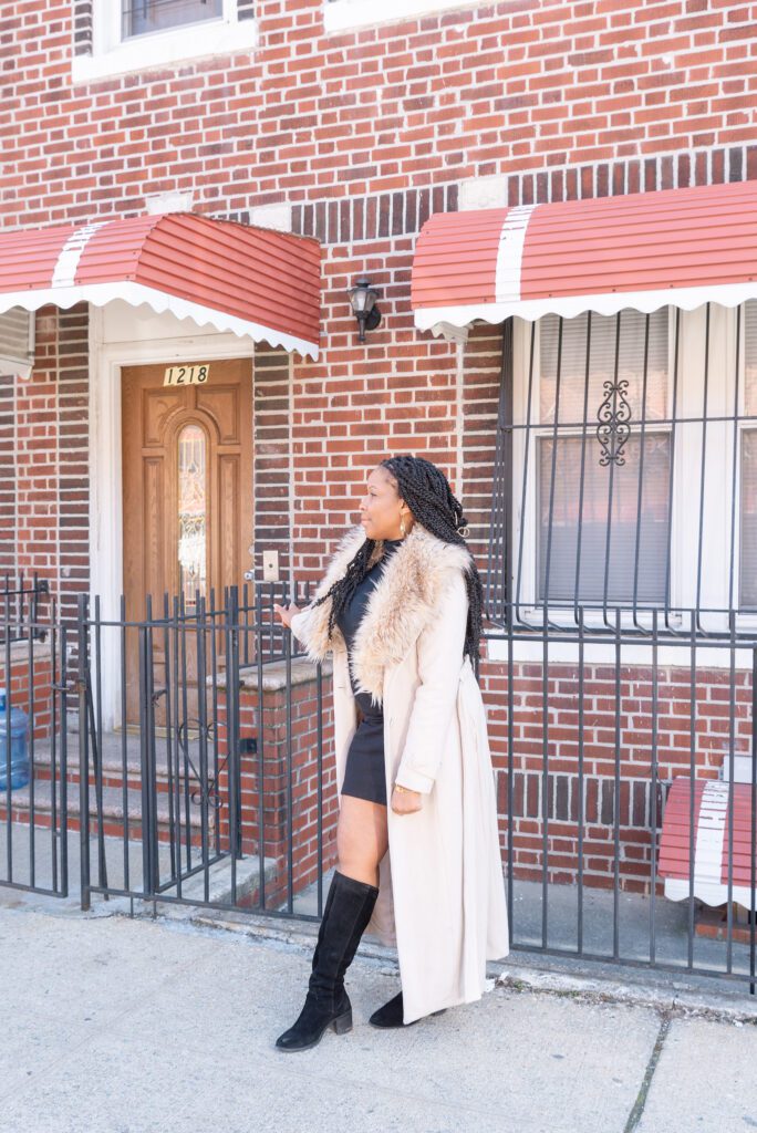 An African American woman business owner standing in front of her childhood home.