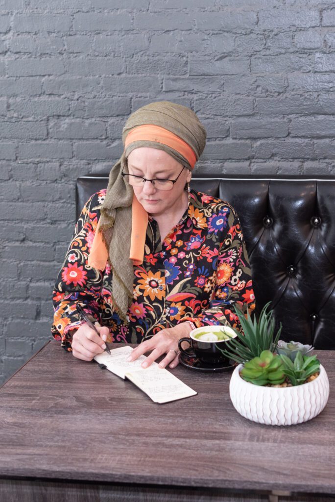 A female digital marketer writing in her notebook and having a cup of coffee at Iconic Coffee in downtown Hackensack, New Jersey.