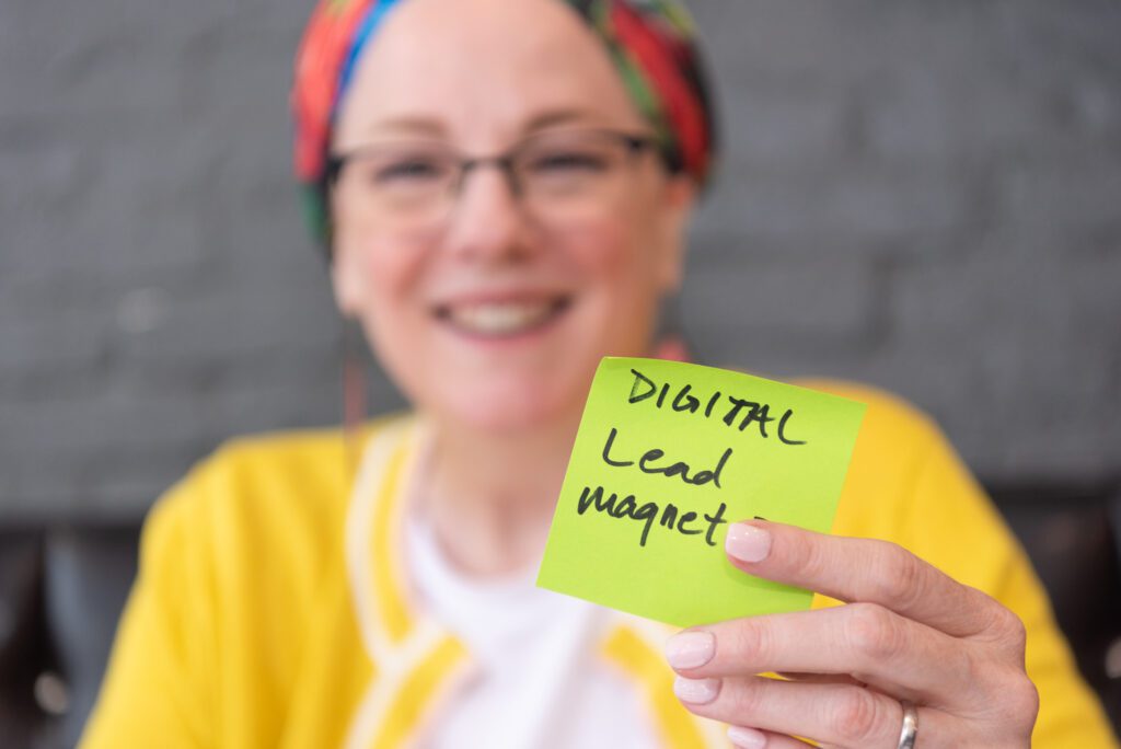 A female digital marketer holding a sticky note with the words "Digital lead magnet".