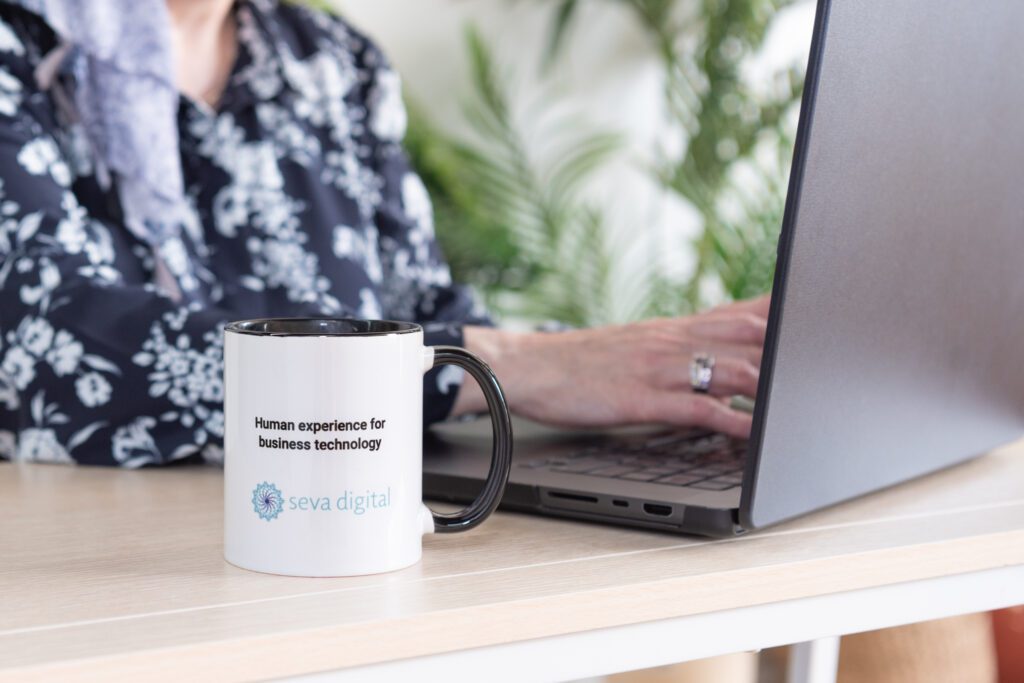 Seva Digital mug with a woman working in the background on her laptop.