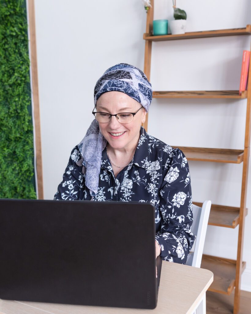 A Jewish woman sitting on a desk and working on her laptop.