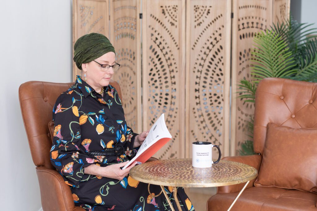 A Jewish woman sitting and reading a book with her coffee mug.