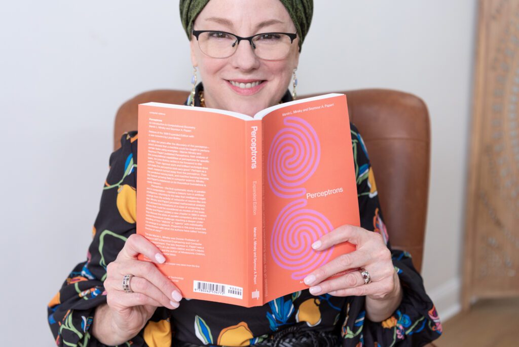 A Jewish woman smiling and holding a book with both hands.