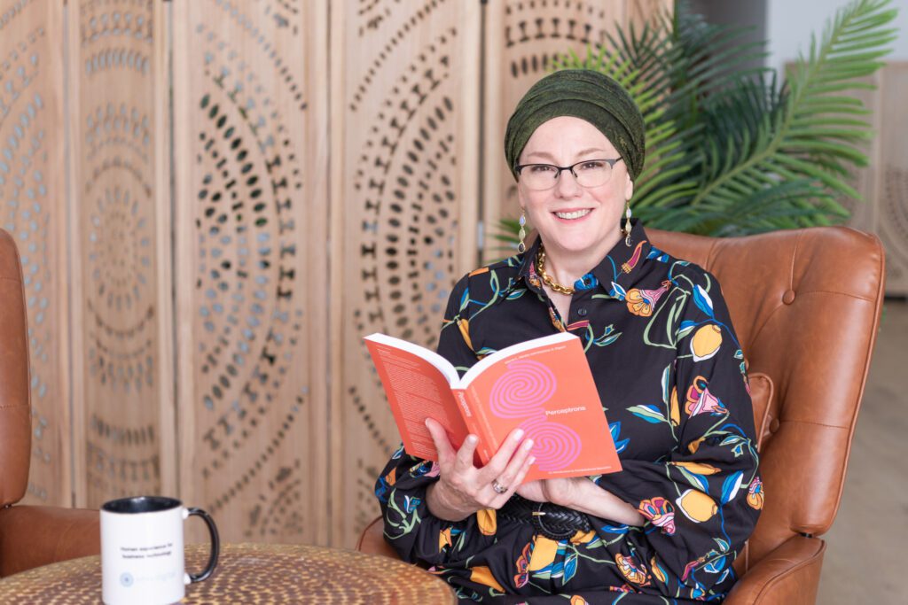 A Jewish woman sitting and reading a book with her coffee mug.