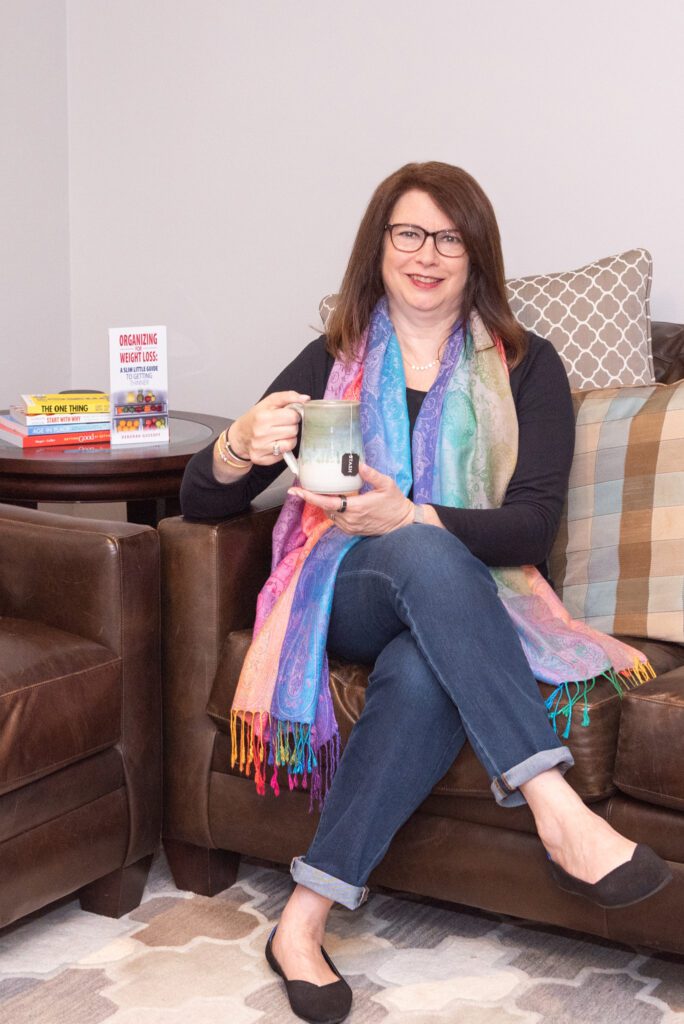 A female professional organizer sitting on a brown couch holding her mug.
