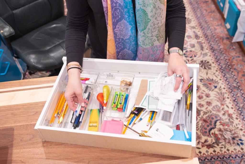A female professional organizer organizing a drawer of stationary.