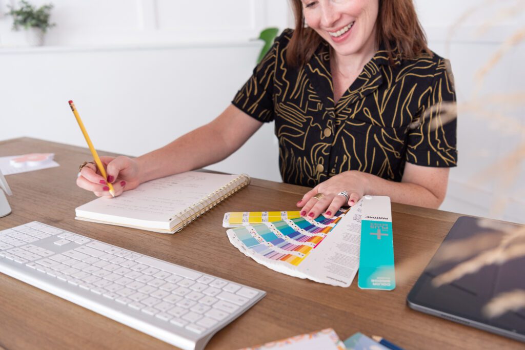 A female graphic and website designer using the Pantone Formula Guide to do a graphic design project.
