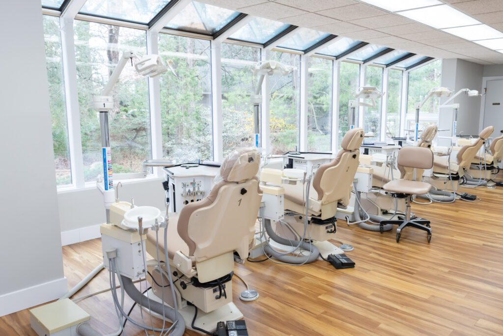 A few dental chairs facing glass windows with a view of the trees at the Ramaswamy Smile Orthodontics office.