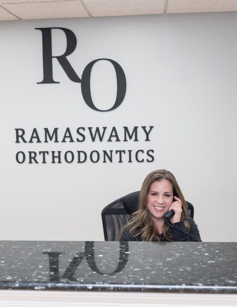 A female receptionist talking on the phone at the Ramaswamy Smile Orthodontics office.