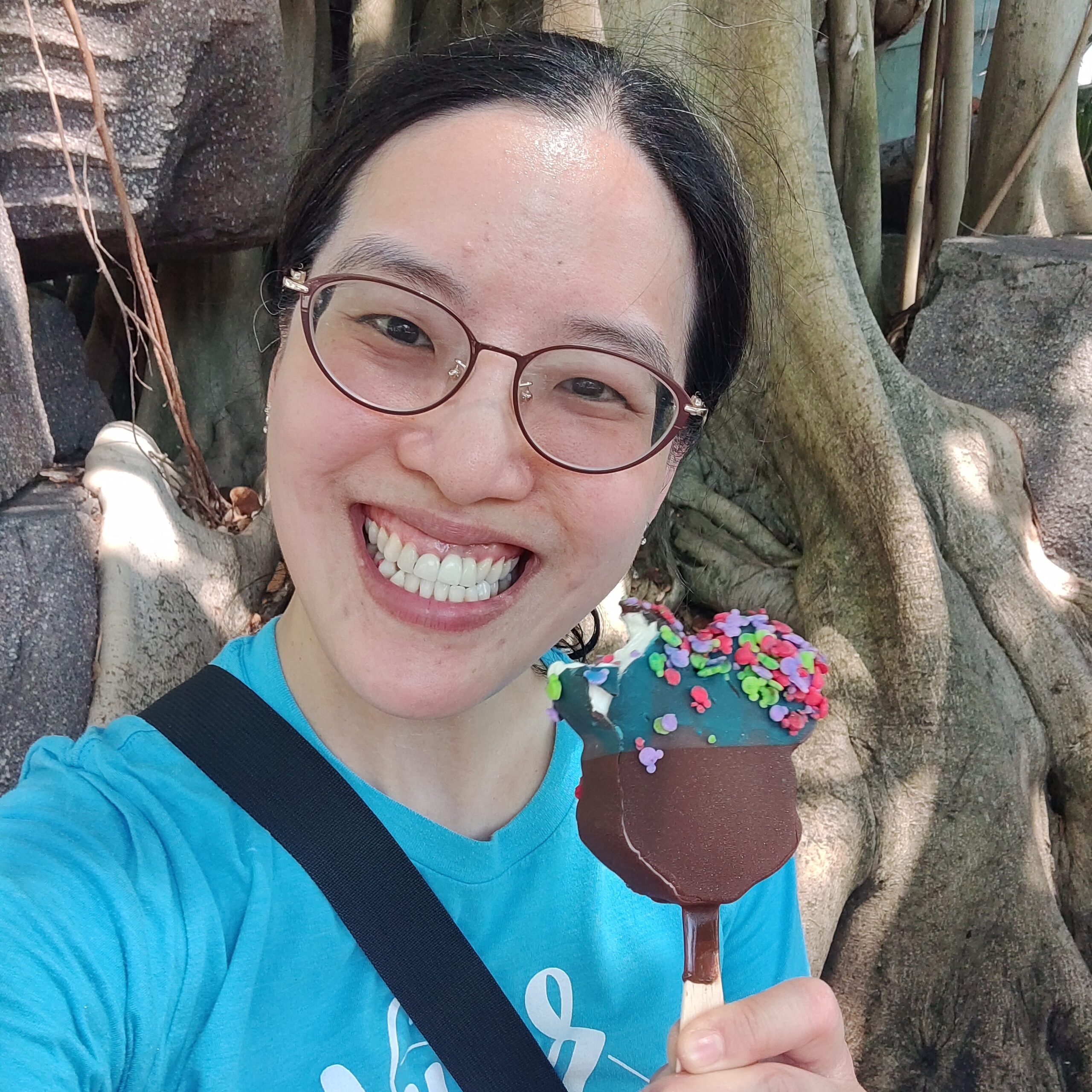 An Asian woman is holding a Mickey-shaped ice cream at Disney World Animal Kingdom.