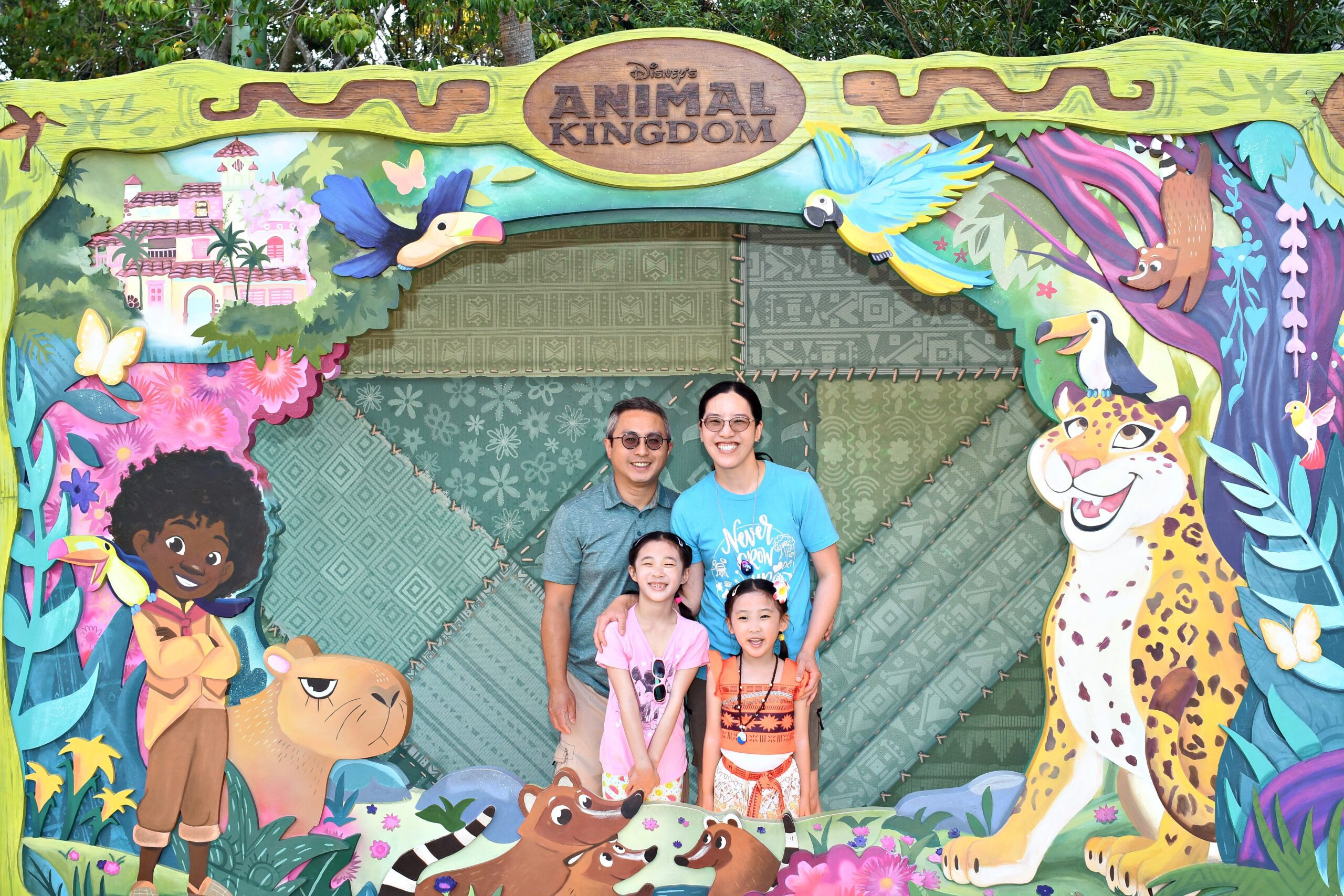 A family of four taking a picture in an Encanto scenery box at Disney World's Animal Kingdom in Orlando, Florida.