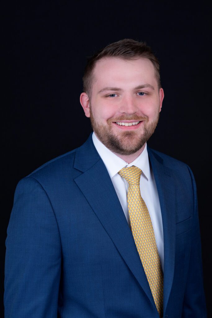 A headshot of a male insurance broker at Hanson & Ryan, Inc. He's wearing a yellow tie and navy blue suit.