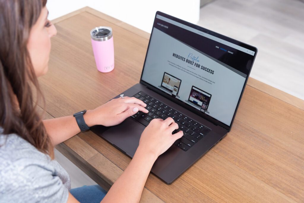 A female website designer is updating her own website on her laptop in her office.