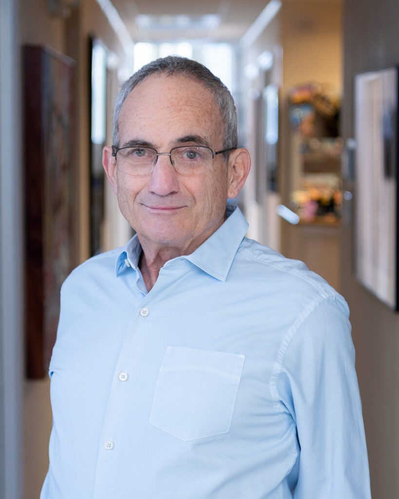 A male dentist smiling in the hallway of his dental practice.