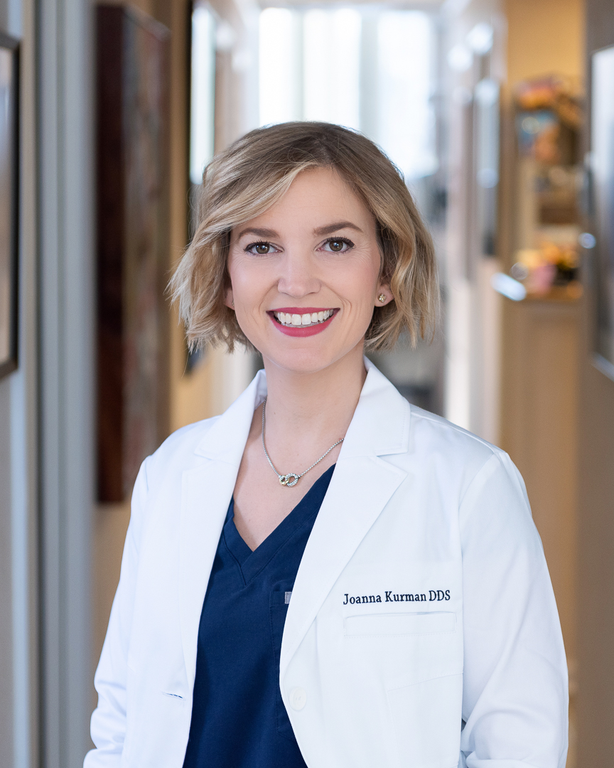 A female dentist smiling in the hallway of her dental practice.