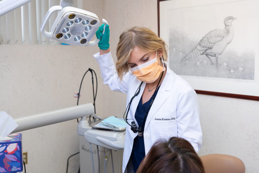 A female dentist getting ready to examine a patient by moving the light.