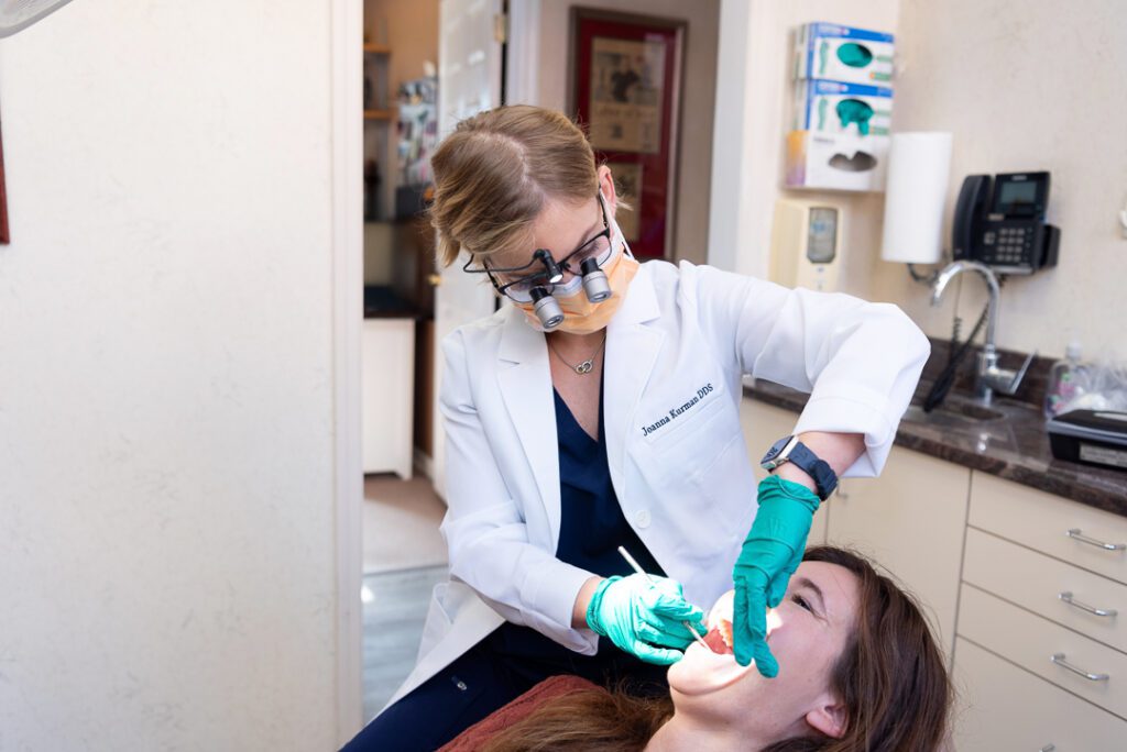 A female dentist examining a female patient in the exam room.