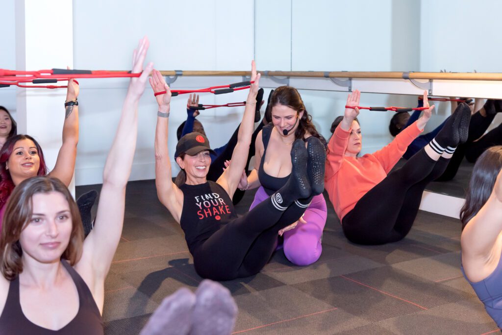 A female instructor helping and guiding a gym member during a Pure Barre class.