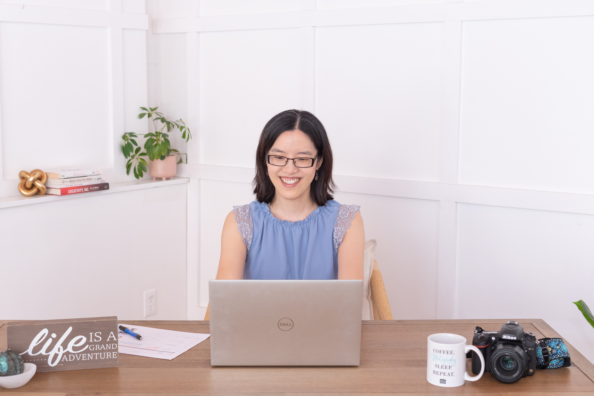 An Asian female personal branding and headshot photographer working on her laptop in her office.