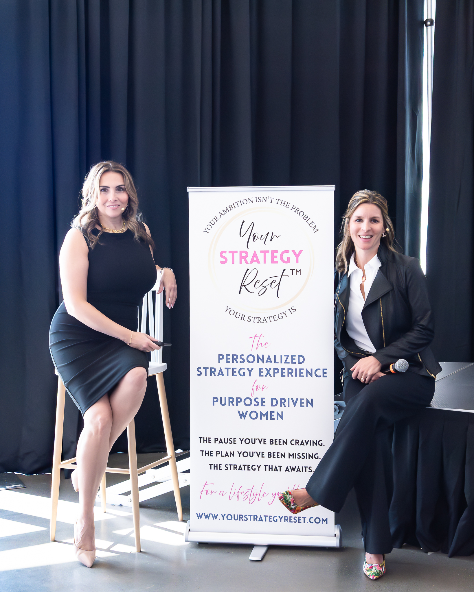 The two coaches and hosts of the Your Strategy Reset event in the Wave Resort sitting and posing next to their sign.