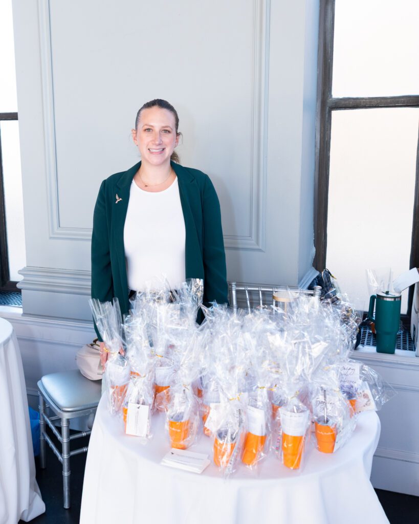 A female psychotherapist posing and smiling at her vendor table.