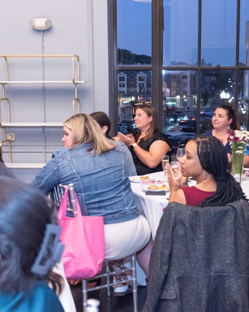 A group of women sitting and clapping at an event.