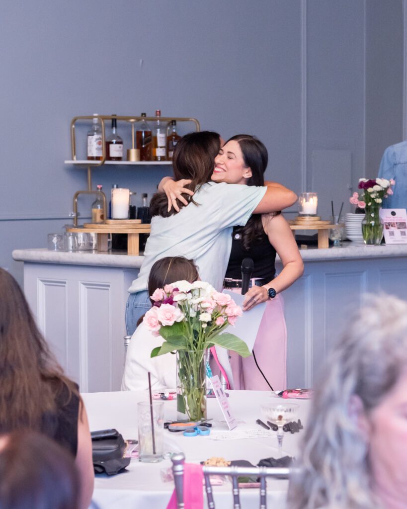 Two women are hugging at an event.