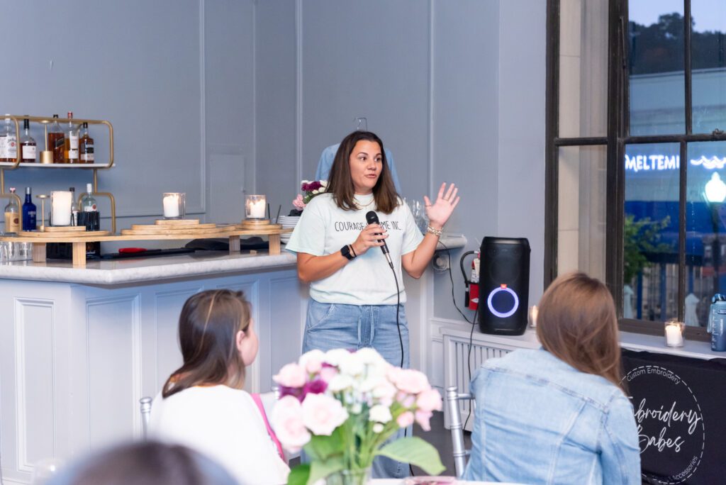 A woman is holding a mic while giving a speech at an event.